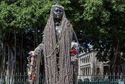 Photo of Liliuokalani statue draped in crown flower lei by Juergen Reichmann. Used by permission