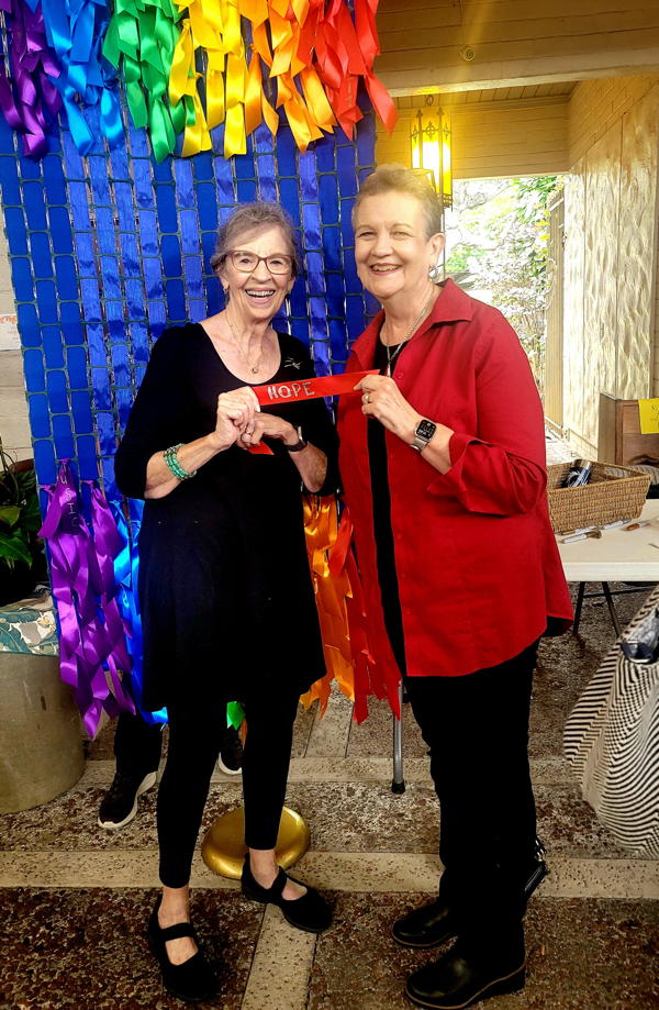 Mary Fastenau and Juditha Murashige hold a ribbon with the word “hope” to add to our new LCH banner.