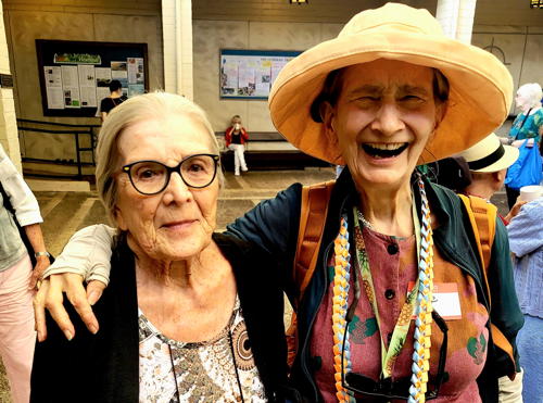 Smiles bloom in the Courtyard! Audrey Keller and Diane Peruchek share a joyful moment of laughter.