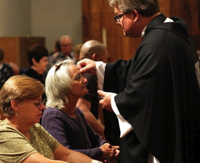 Pastor Jeff Lilley marks the foreheads of members of the congregation with ashes during the Ash Wednesday Liturgy.