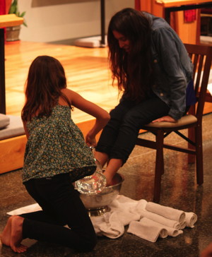 Two sisters wash each other’s feet as part of the Maundy Footwashing