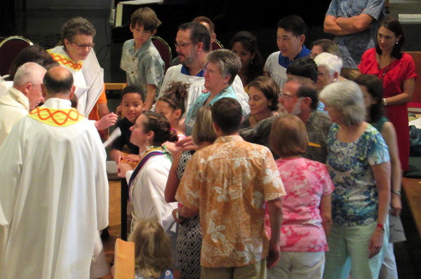 Members of the congregation gather around to lay on hands as part of the Installation